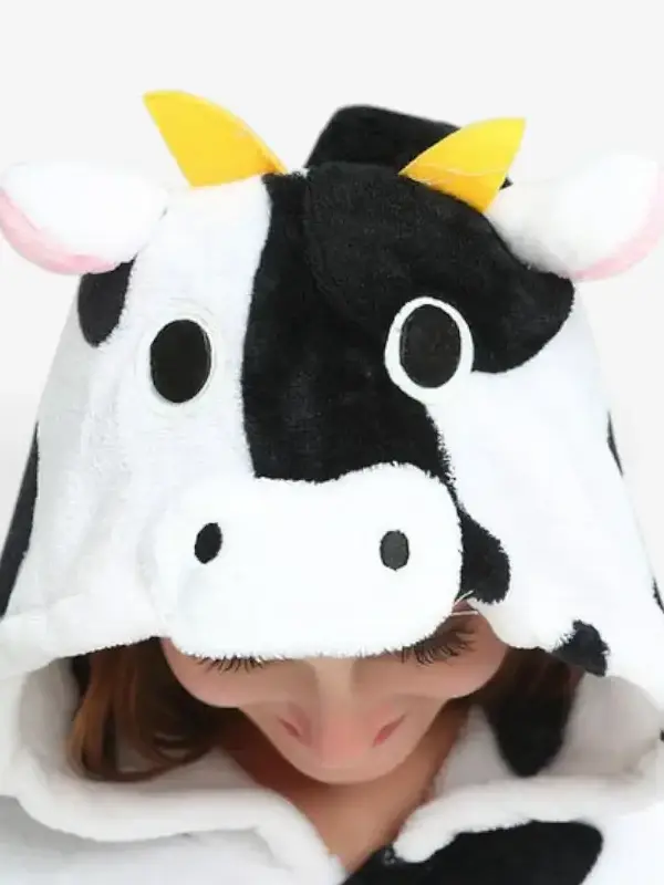 Close-up of the cow onesie hood featuring plush horns, ears, and a cute cow face.